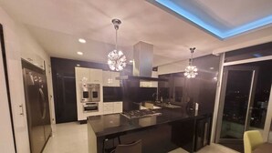 Una cocina moderna con una isla central, electrodomésticos de acero inoxidable e iluminación colgante.