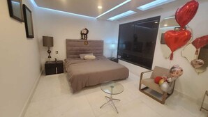 Un dormitorio moderno con cama, mesita de noche, lámpara y una silla con globos.