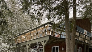 Una cabaña de madera con un balcón, rodeada de árboles cubiertos de nieve.