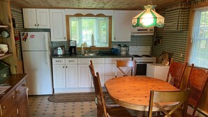 Una cocina con una mesa y sillas de madera, un refrigerador y una estufa.