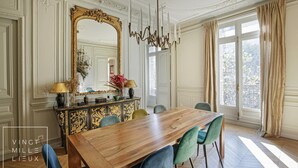 Ein Esszimmer mit Holztisch, Stühlen, einem großen Spiegel und einer Kristallleuchtre.