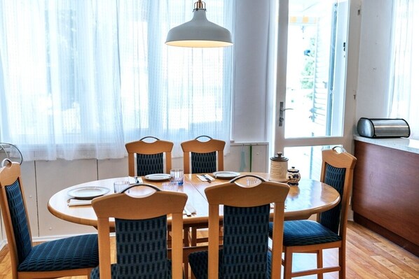 Un coin repas avec une table ronde, six chaises et un luminaire suspendu.