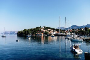 Un port de plaisance avec des bateaux, une petite île avec des bâtiments et des montagnes en arrière-plan.