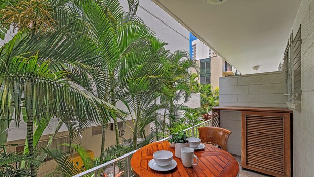 Ein Balkon mit Holztisch, Stühlen und einem Blumentopf.