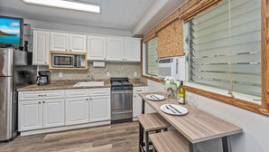 Eine moderne Küche mit weißen Schränken, Edelstahlgeräten, einer Holz Arbeitsplatte und einem Essbereich mit Tisch und Bänken.