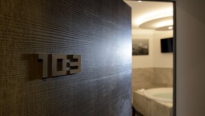 Une salle de bain moderne avec une grande baignoire, un mur à texture et une poignée de porte bien visible.