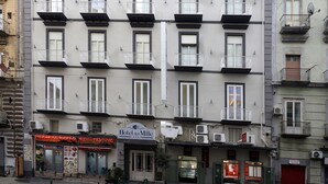 Un hôtel à plusieurs étages doté de balcons, de climatiseurs et d’une façade avec une enseigne.