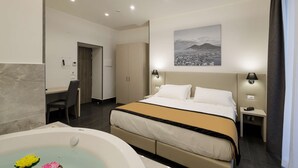 Une chambre d’hôtel moderne équipée d’un grand lit, d’un bureau, d’une chaise, d’une lampe de bureau, d’une table de chevet et d’une lampe fixée au mur.