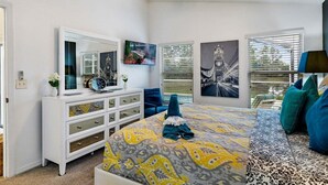 A bedroom with a bed, a dresser, a ceiling fan, and artwork on the walls.