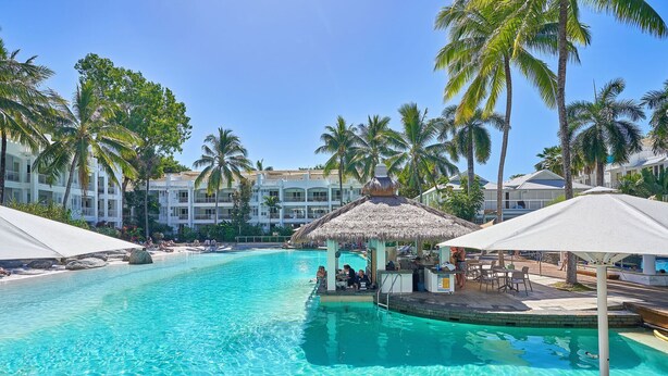 A resort pool area with clear blue water, lounge chairs, and palm trees. - Beautifully appointed 1 Bedroom Ground Floor Beach Club Lagoon View Apartment (Palm Cove)