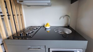 A compact kitchen with a gas stove, a sink, and a microwave. - Jönköping Hotel Apartments (Jonkoping)
