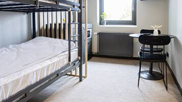 A bunk bed room with a small table and a TV mounted on the wall.