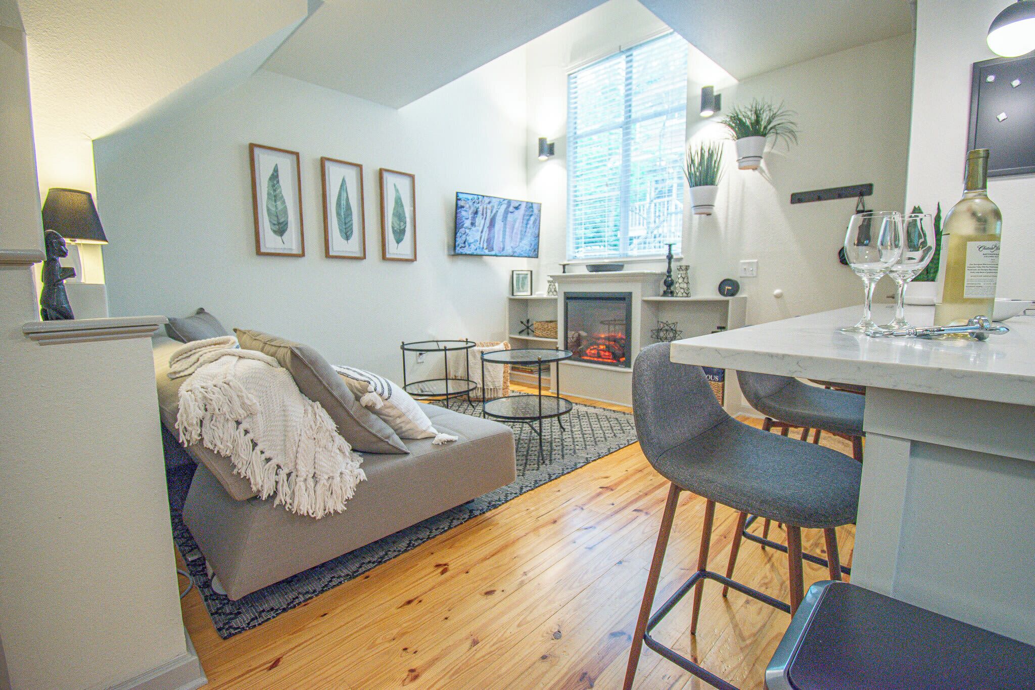Una sala de estar moderna con un sofá, una mesita de centro y una zona de comedor con sillas.