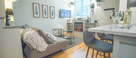 Una sala de estar moderna con un sofá, una mesita de centro y una zona de comedor con sillas.
