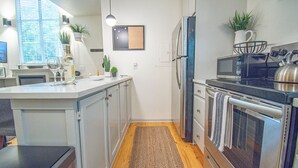 Una cocina moderna con una isla central, electrodomésticos de acero inoxidable y suelo de madera.