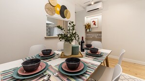 A modern dining area with a long table set for four, featuring striped placemats and black bowls on teal plates. - Waou Don Quixote Las Letras (Madrid)