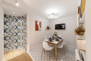 A modern dining area with a wooden table, white chairs, and patterned floor tiles. - Waou Don Quixote Las Letras (Madrid)
