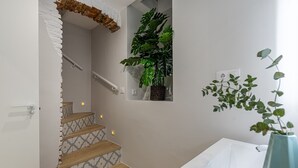 A staircase with patterned tiles, a white bathtub, and a potted plant. - Waou Don Quixote Las Letras (Madrid)