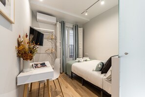 A modern bedroom with a bed, bedside table, and a small desk with a lamp and a magazine.