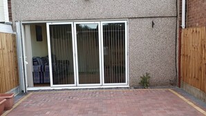 Un patio con piso de ladrillo, puerta corredera de vidrio y una planta pequeña.
