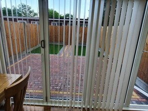 Een terras met houten omheining, een betegelde vloer en een schuifdeur.