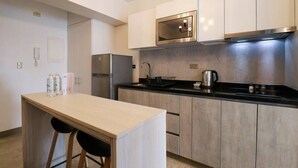 A modern kitchen with a central island, stainless steel appliances, and light wood cabinetry.