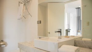 Une salle de bain moderne avec un grand lavabo rectangulaire, un miroir et des toilettes.