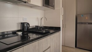 Une cuisine moderne dotée d’un plan de travail noir, d’appareils électroménagers en acier inoxydable et d’un four à micro-ondes encastré.