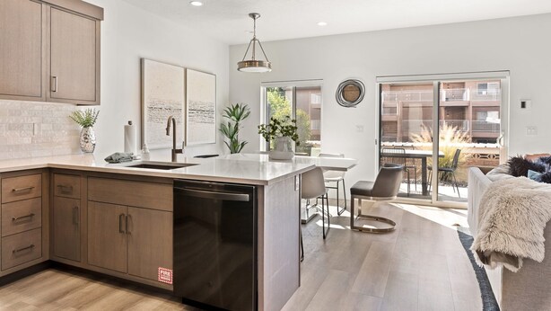 Una cocina moderna con lavavajillas, armarios de madera y un comedor con mesa y sillas.