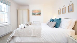 A bedroom with a large bed, a wardrobe, a painting on the wall, and a window with curtains.