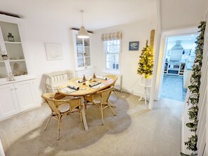 A dining area with a round table, wicker chairs, and a Christmas tree.