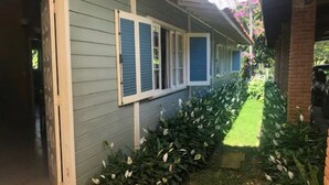 Un porche abrité, avec un chemin menant à une maison aux volets bleus.