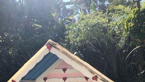 Une petite maison rose et bleue, avec une véranda et des fenêtres.