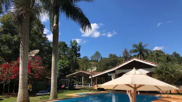Une piscine bordée de palmiers et une maison en arrière-plan.