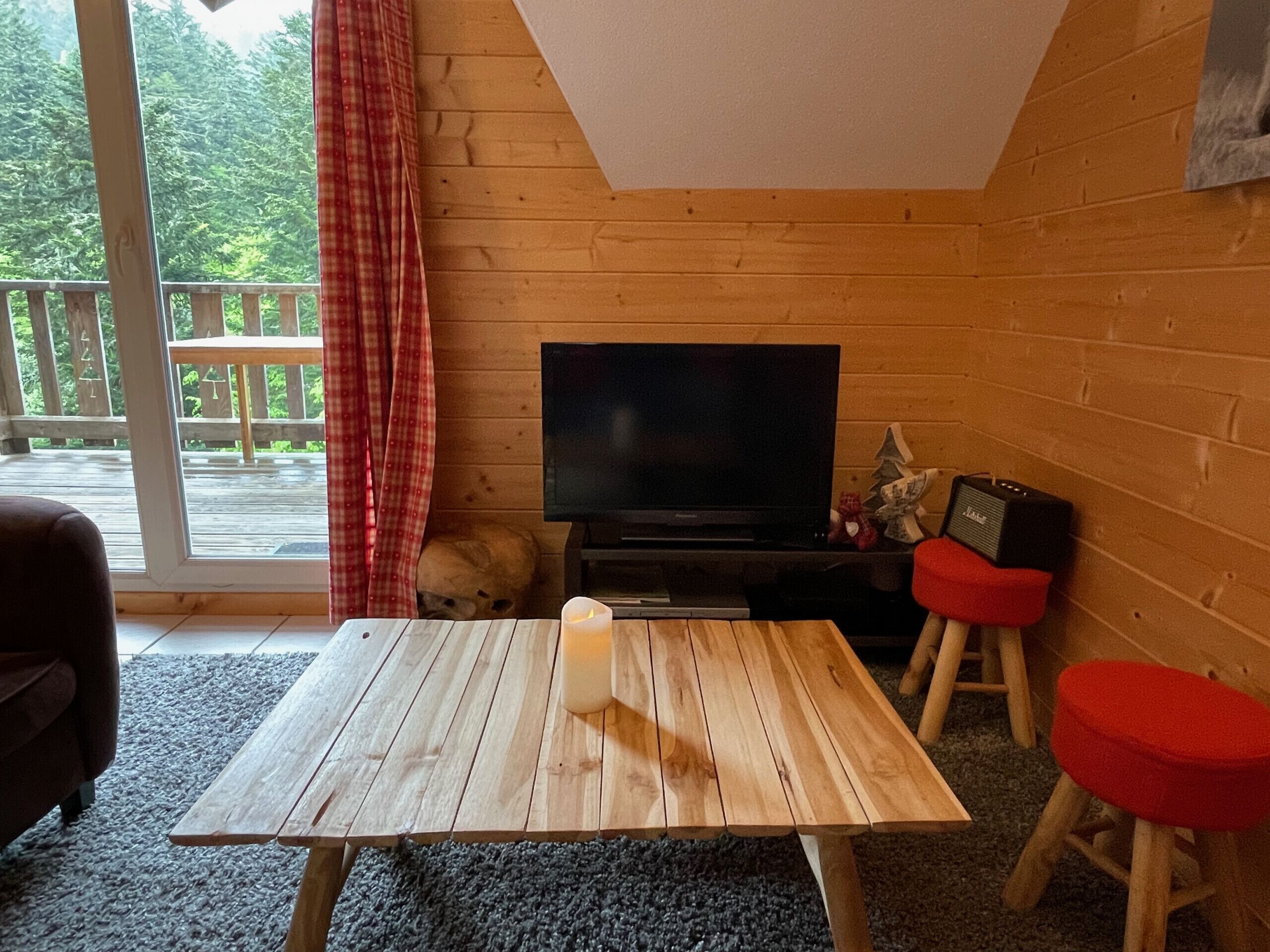A cozy room with a wooden table, a television, and a red chair.