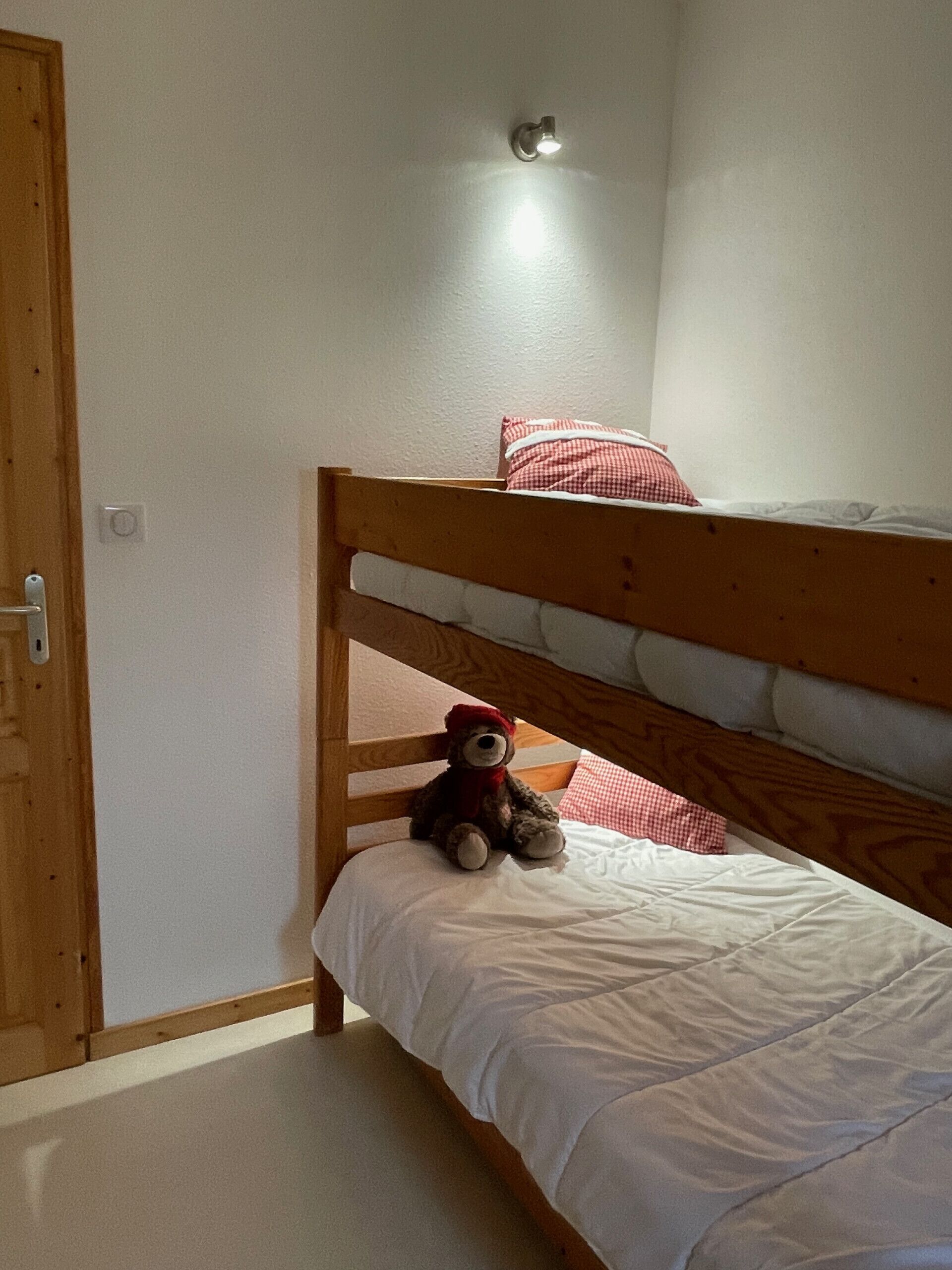 A bunk bed room with a teddy bear on the lower bunk.