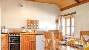 Ett kök med träskåp, en brödrost, en vattenkokare, en kaffemaskin och ett frukostbord med croissanter och apelsinjuice.