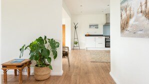 Una cocina moderna con armarios blancos, suelo de madera y un cuadro en la pared.
