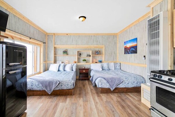 Une chambre de taille modeste comprenant deux lits, un coin cuisine et une petite table.