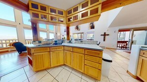 Een ruime keuken met houten kastjes, een groot eiland en uitzicht op de omgeving.