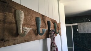 A wooden wall with decorative fish hooks and a floral curtain. - Seaside Cottage in Beautiful Charlo’s Cove (Charlo's Cove)