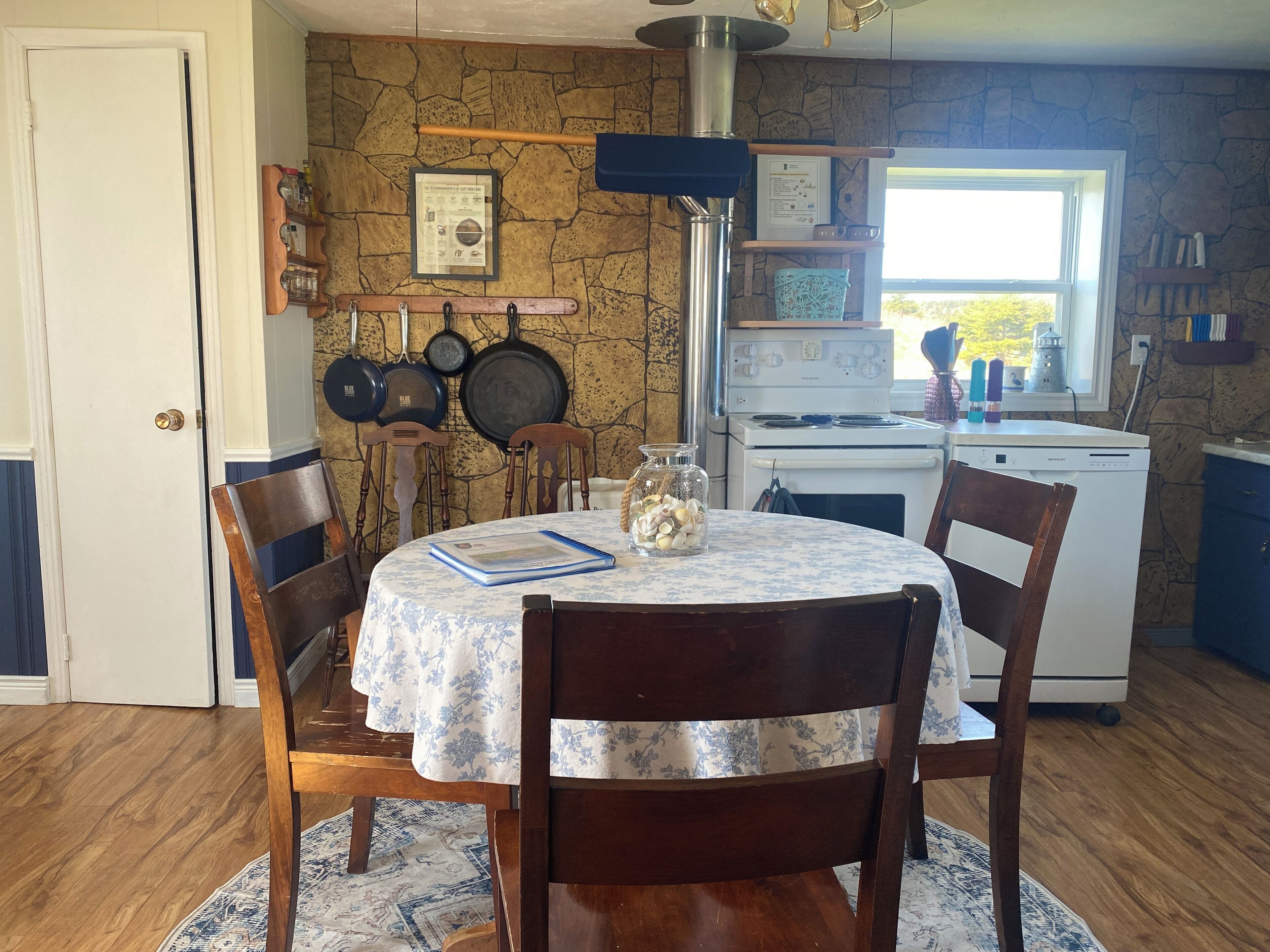 A dining area with a round table, chairs, a stove, and a window.