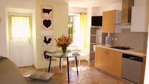 Cozinha compacta com área de refeições, sofá e televisão.