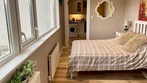 A bedroom with a bed, a radiator, a window, and a view of a laundry area. - 1 Bed Flat - Sleeps 5 - Parking - Garden - Pets (Larne)