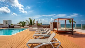 Eine Holzterrasse mit Pool, Liegestühlen und einem Himmelbett.