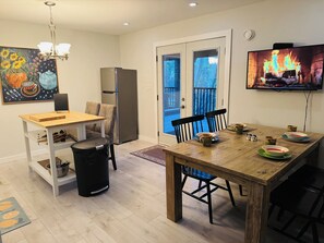 Cozy living space with a dining area and kitchen, featuring a wooden table, chairs, and a stainless steel refrigerator.