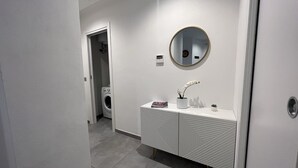 Een moderne badkamer met een wit wastafelmeubel, een ronde spiegel en een ingebouwde wasmachine.