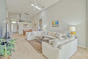 A spacious living room with a sectional sofa, a coffee table, and a ceiling fan.
