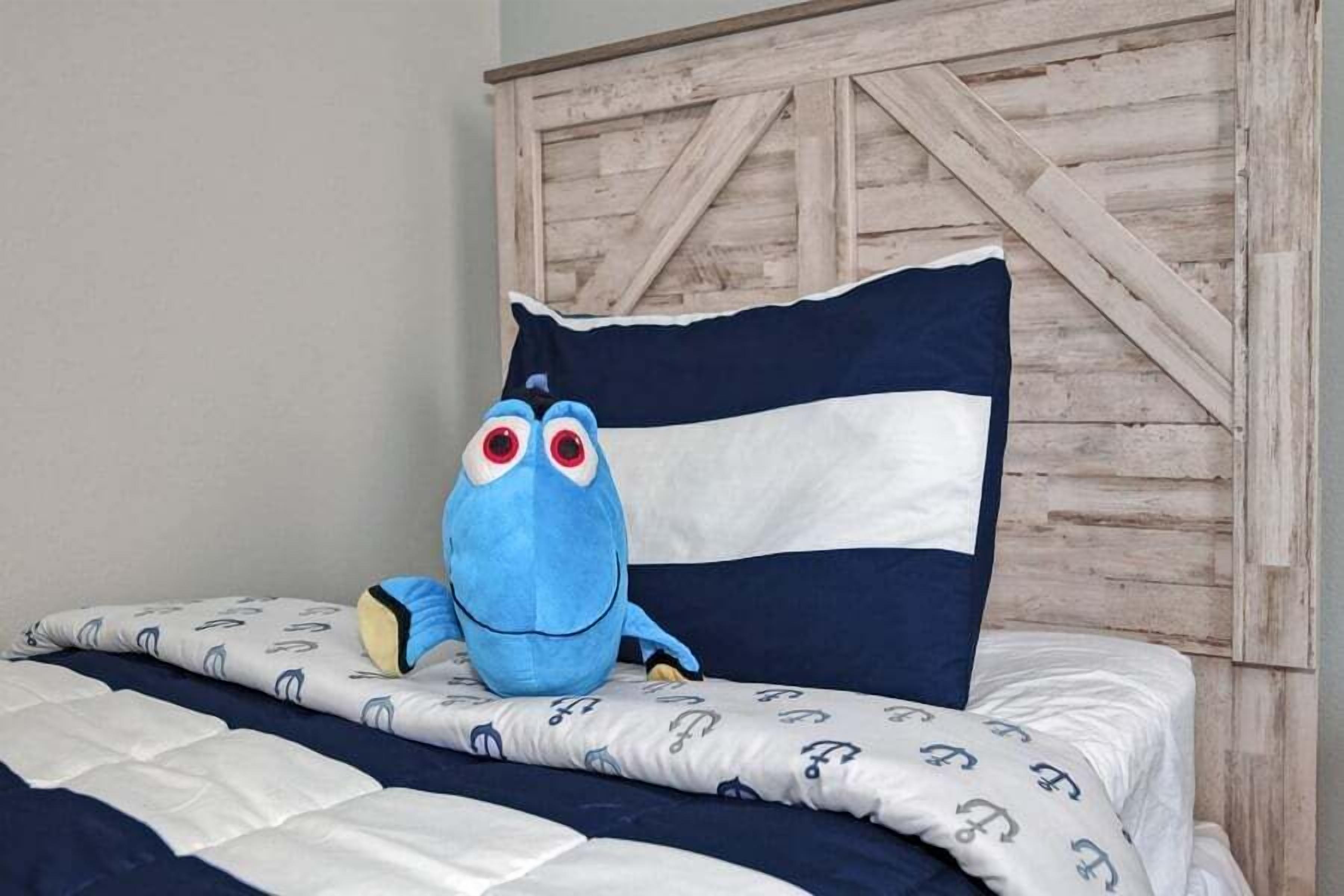 A bed with a blue plush toy, a striped pillow, and a patterned blanket.