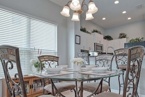 A dining area with a glass table, metal chairs, and a chandelier.